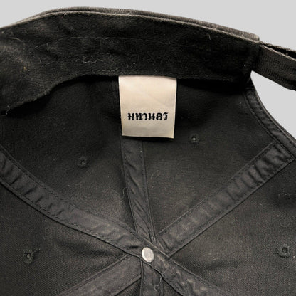 Interior view of a black Raree Finds Mahanakhon cotton strapback hat showing the authentic woven brand tag