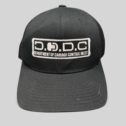 Raree Finds black Marvel Damage Control trucker hat with D.O.D.C. West embroidered patch and mesh back panels.