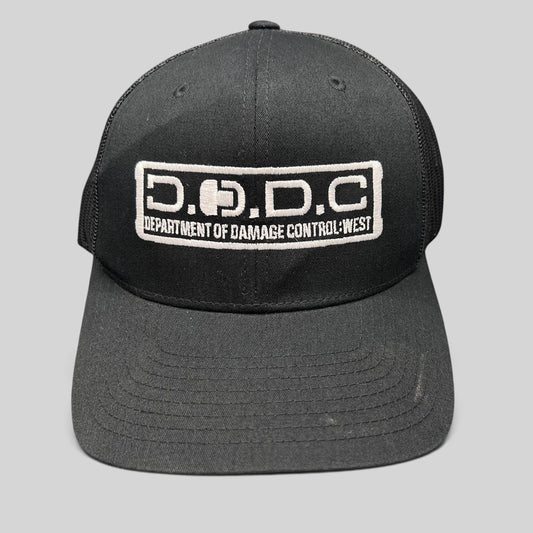 Raree Finds black Marvel Damage Control trucker hat with D.O.D.C. West embroidered patch and mesh back panels.