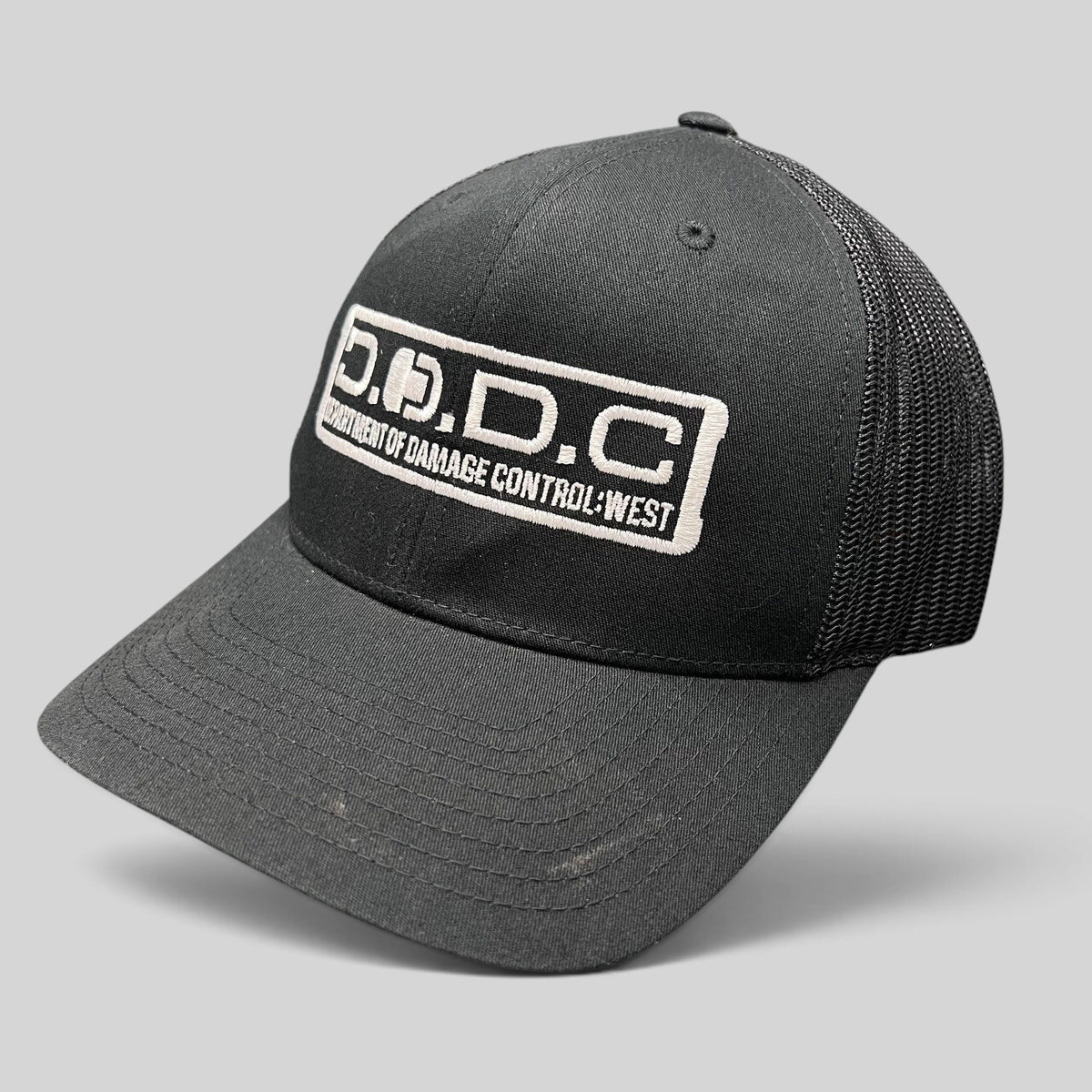 Raree Finds black Marvel Damage Control D.O.D.C. West trucker hat with mesh back and adjustable snapback closure.