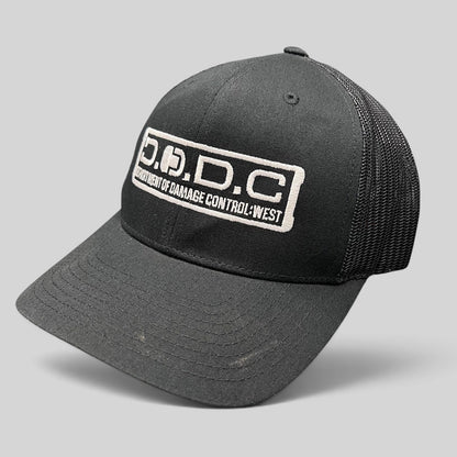 Raree Finds black Marvel Damage Control D.O.D.C. West trucker hat with mesh back and adjustable snapback closure.