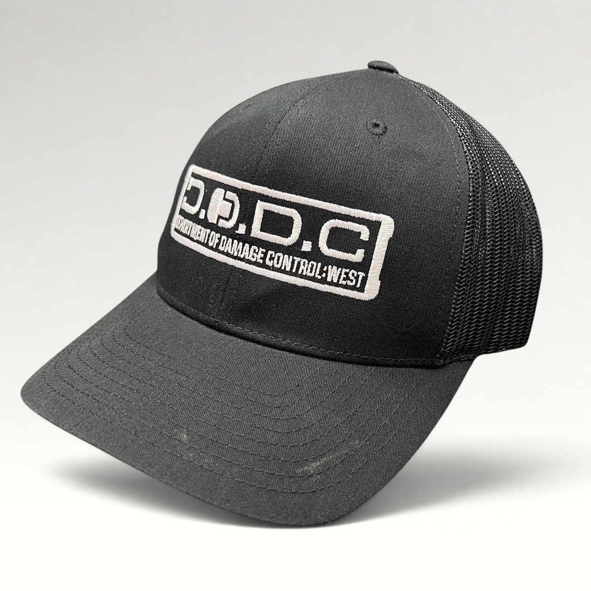 Raree Finds black Marvel Damage Control D.O.D.C. West trucker hat with mesh back and adjustable snapback closure.