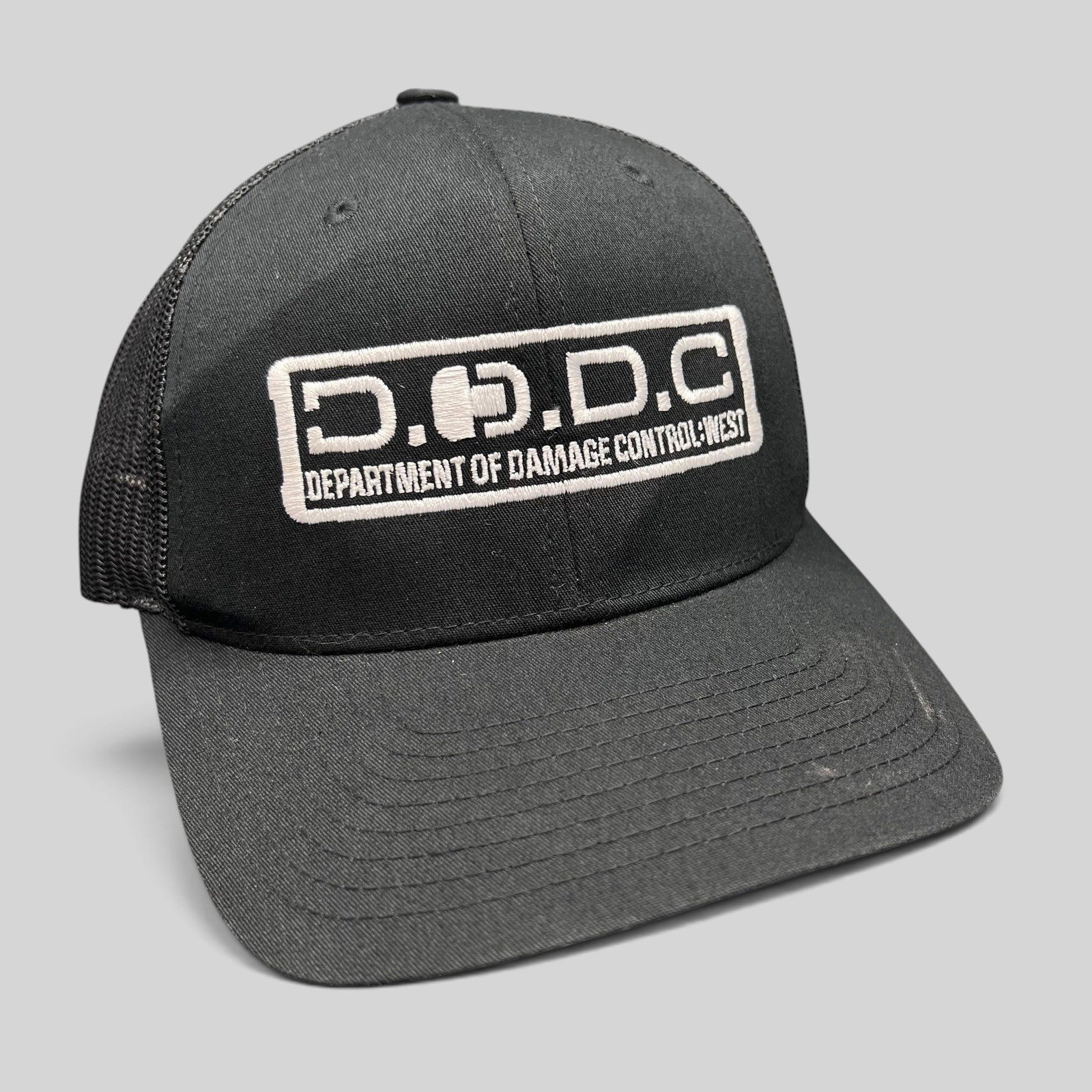Raree Finds black Marvel Damage Control trucker hat with D.O.D.C. West patch and adjustable snapback closure