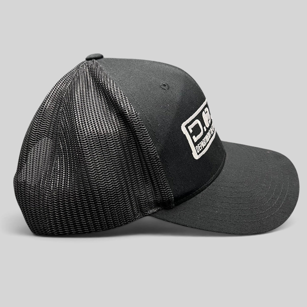 Raree Finds Marvel Damage Control black trucker hat with mesh back and D.O.D.C. West patch, side profile view.
