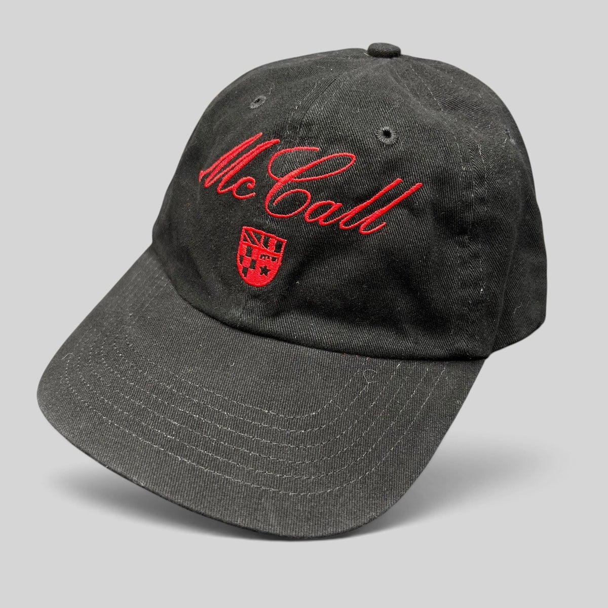Raree Finds McCall Motor Works black strapback hat with red script embroidery and crest on a dark background