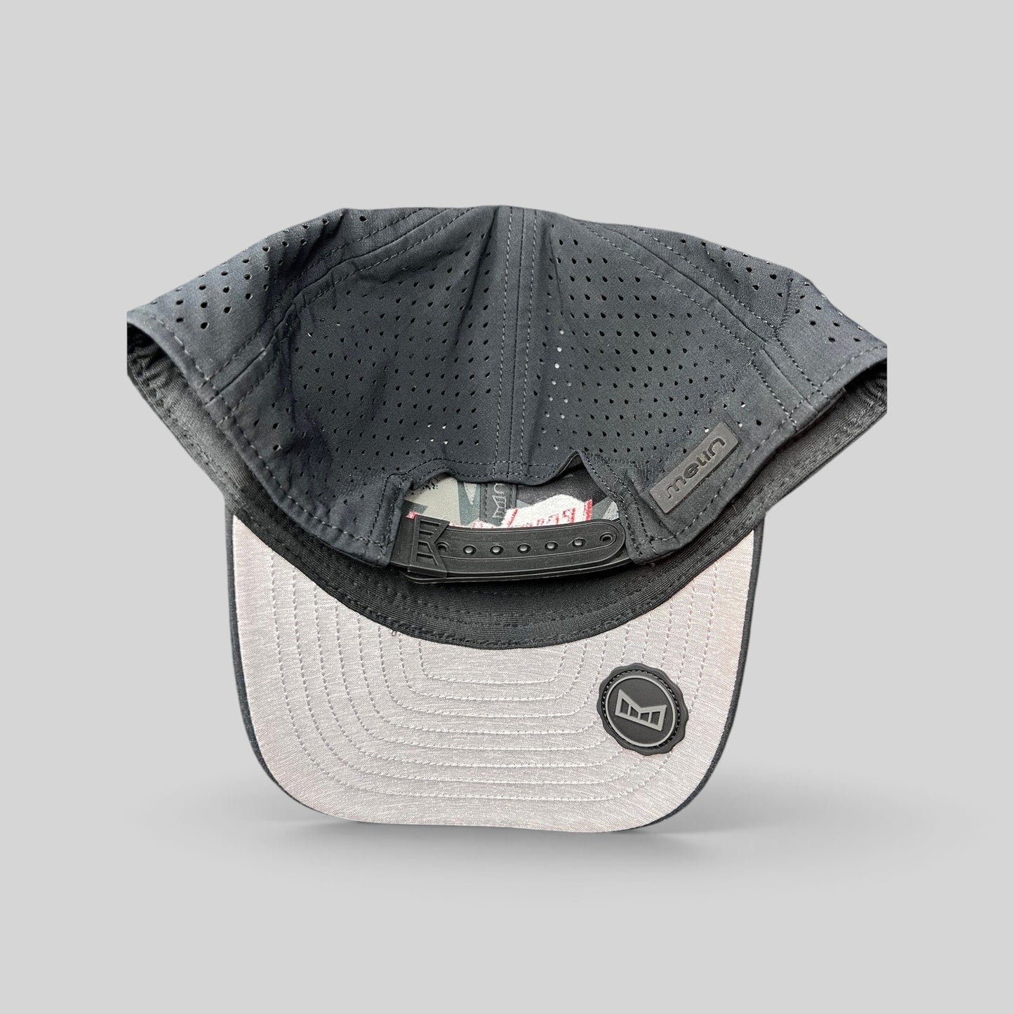 Raree Finds Melin Leave the World Behind snapback hat showing the perforated grey crown and adjustable strap interior.