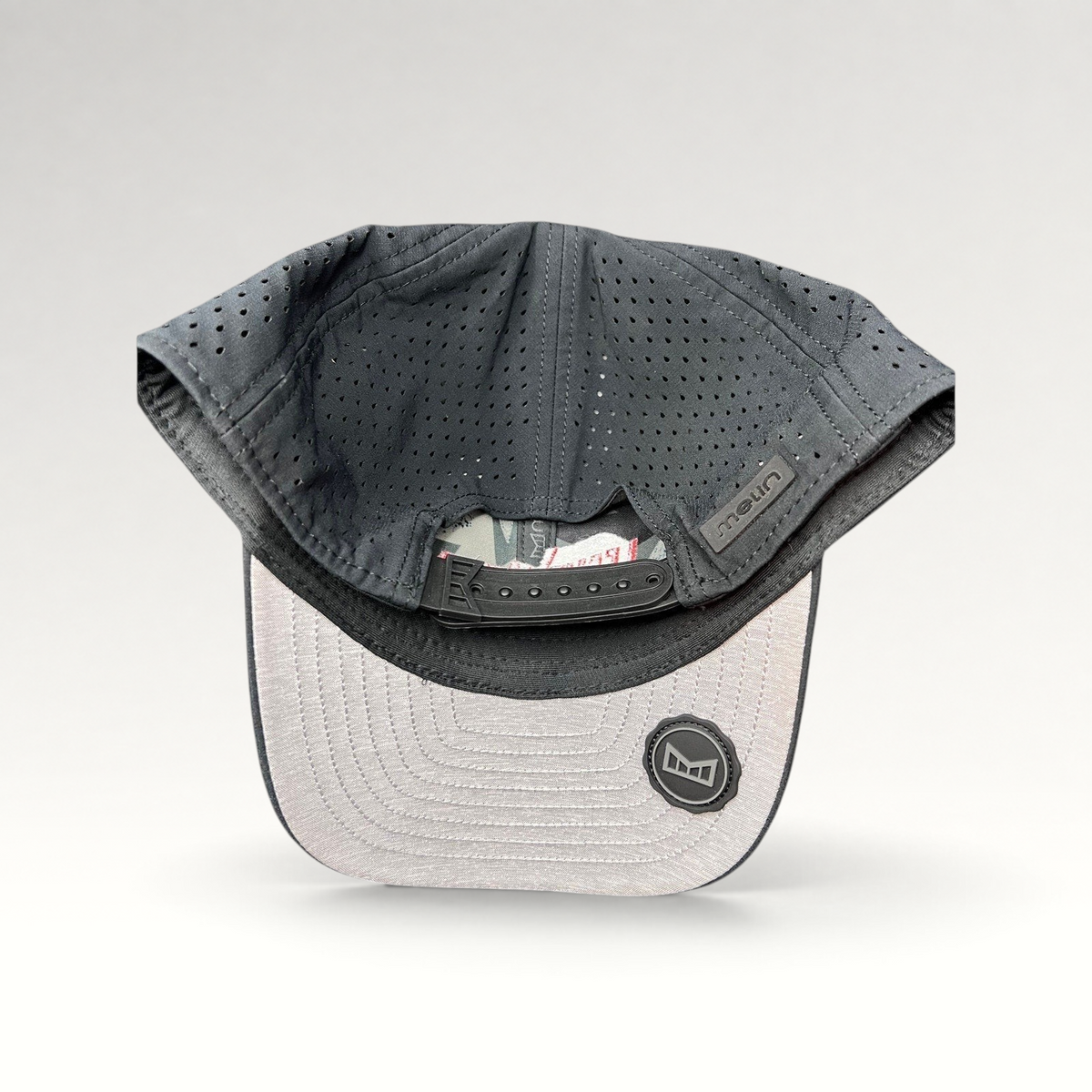 Raree Finds Melin Leave the World Behind snapback hat showing the perforated grey crown and adjustable strap interior.