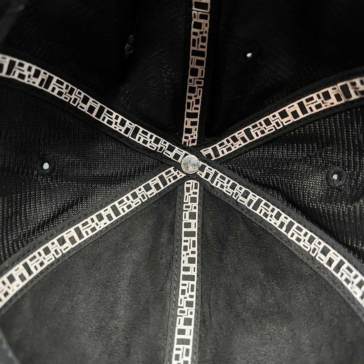 Interior view of a Raree Finds Metal Noir black strapback hat showing branded geometric pattern seam taping