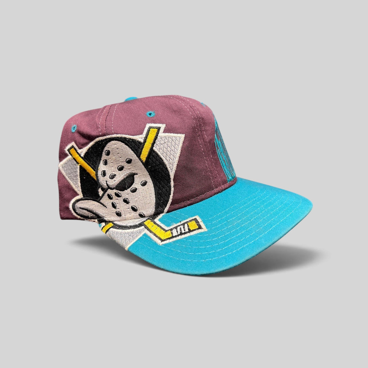 Raree Finds vintage 90s Anaheim Mighty Ducks snapback hat with eggplant crown, teal brim, and goalie mask embroidery.