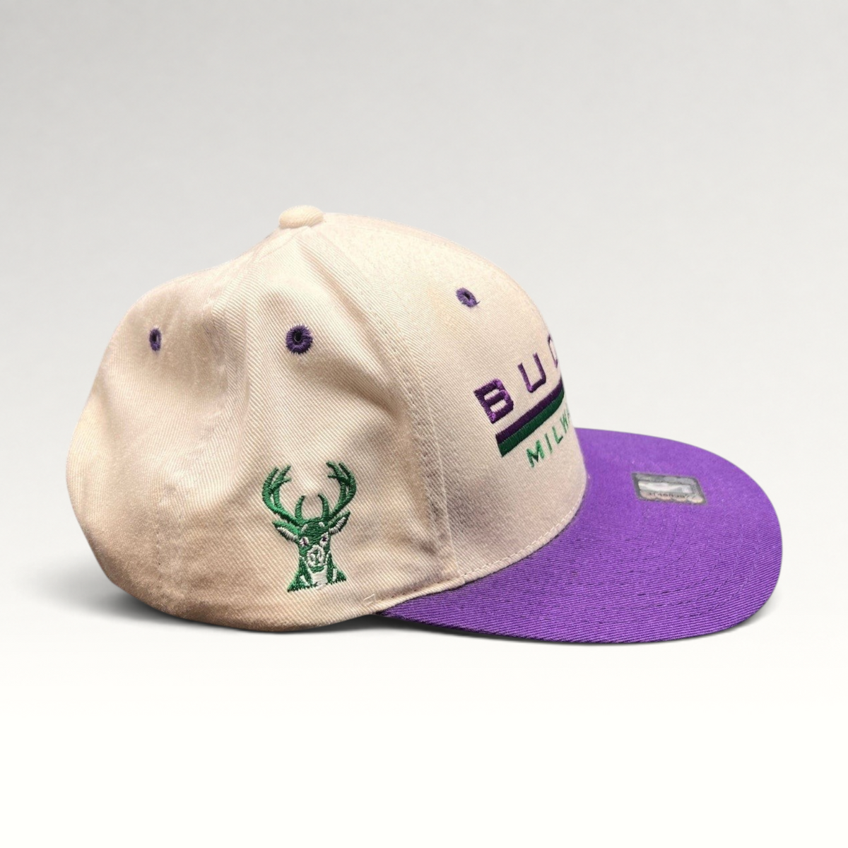 Raree Finds vintage 1990s Milwaukee Bucks snapback hat with white crown, purple brim, and embroidered team logo.