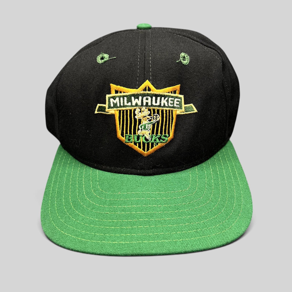 Raree Finds vintage Milwaukee Bucks New Era snapback hat with embroidered shield logo, black crown, and green brim.