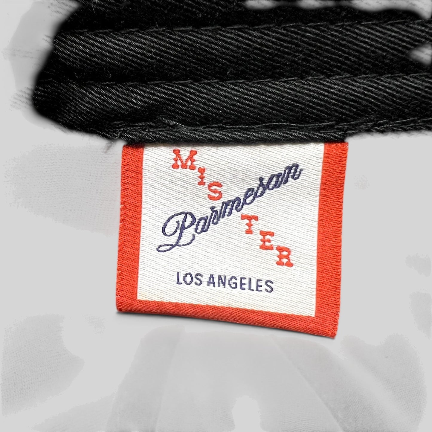 Raree Finds Mister Parmesan Los Angeles clothing brand label tag on a black cotton strapback hat