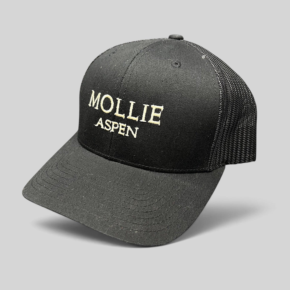 Raree Finds black Yupoong Classics trucker hat with MOLLIE Aspen embroidered logo and breathable mesh back panels.