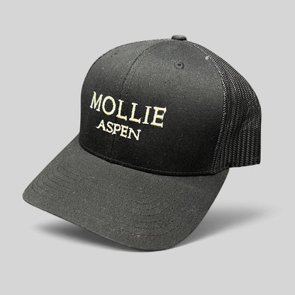 Raree Finds black Yupoong Classics trucker hat with MOLLIE Aspen embroidered logo and breathable mesh back panels.