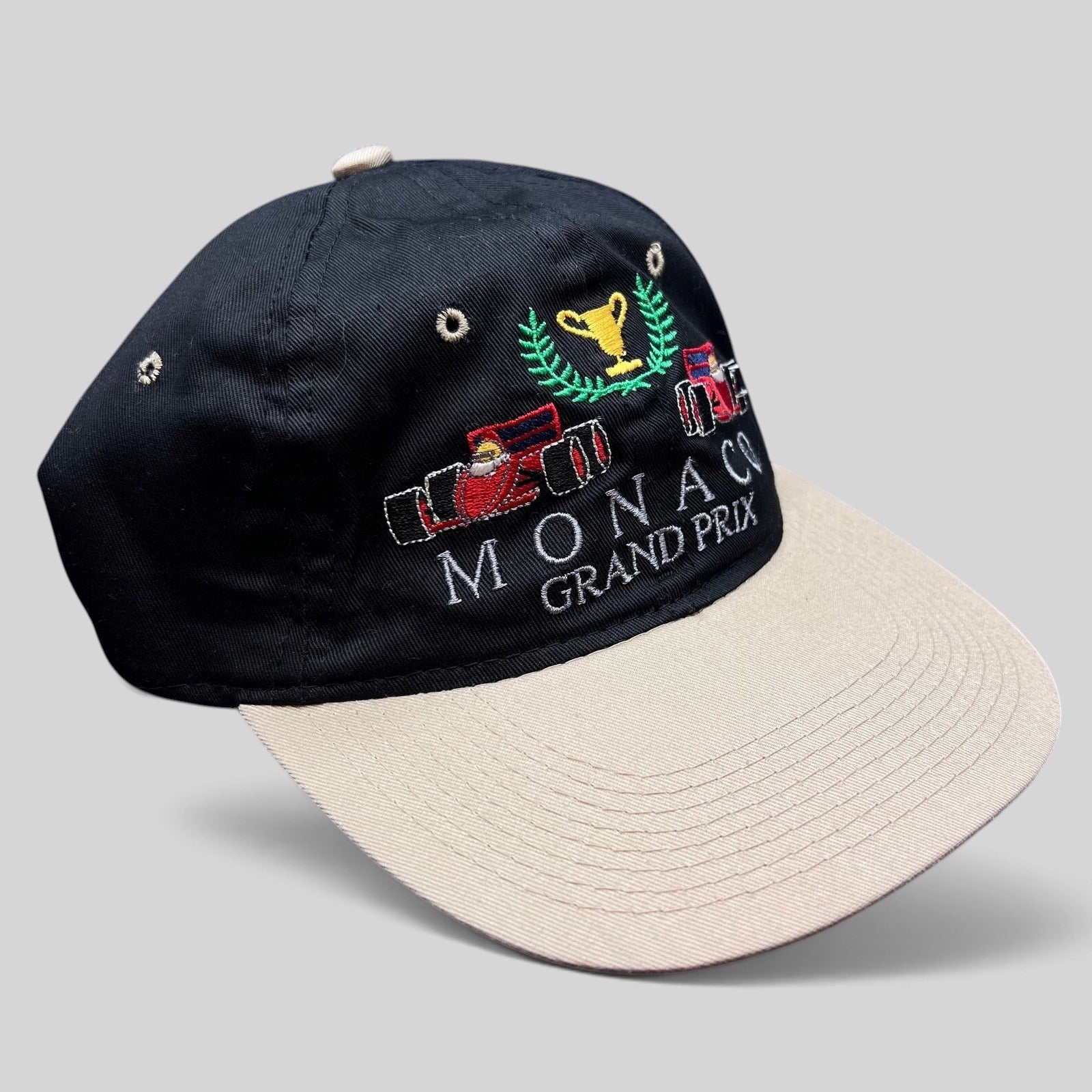 Raree Finds vintage Monaco Grand Prix racing hat with black crown, beige brim, and embroidered F1 car graphic.