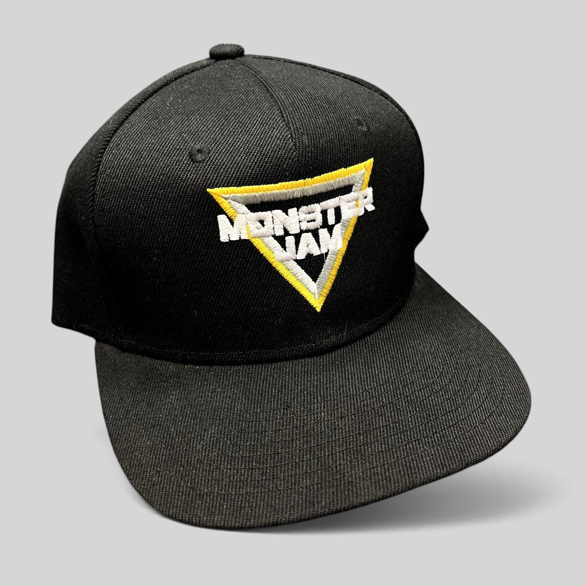 Raree Finds black snapback hat featuring an embroidered triangular Monster Jam logo in white, black, and yellow.