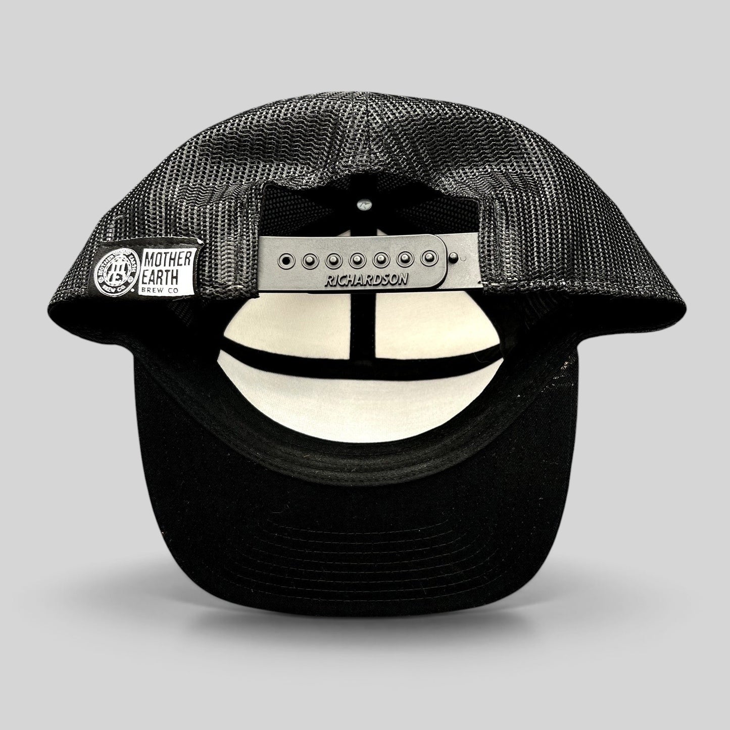 Raree Finds Mother Earth Brew Co Richardson black mesh trucker hat showing the adjustable snapback closure and label