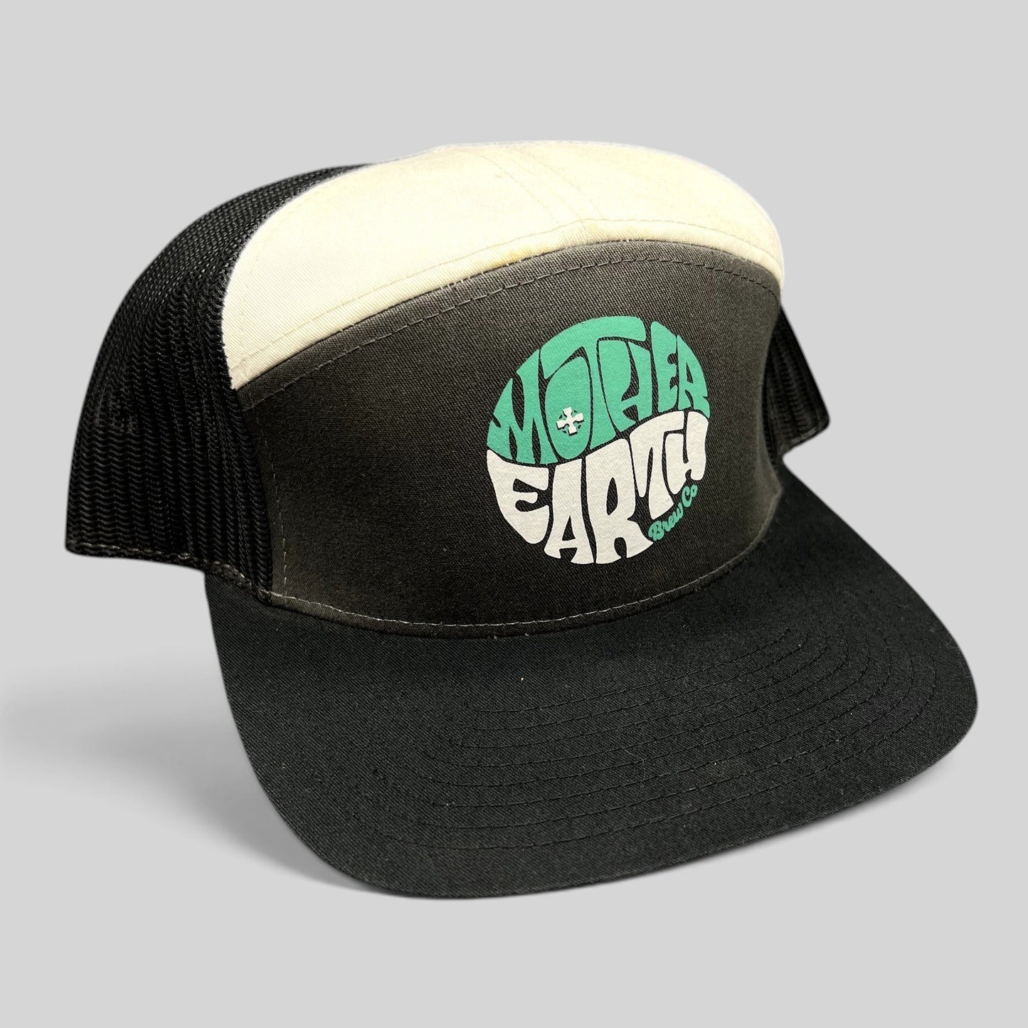 Raree Finds Mother Earth Brew Co Richardson trucker hat with black and cream panels, mesh back, and teal logo graphic.
