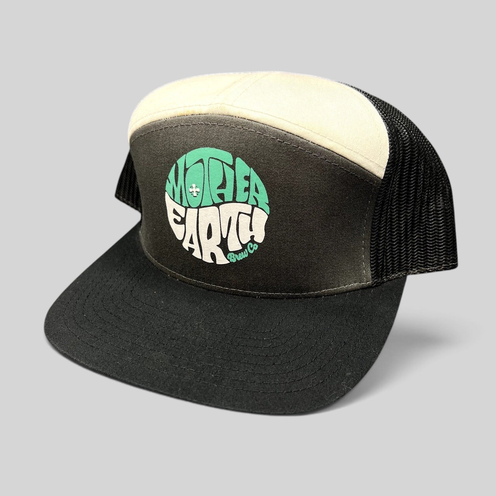 Raree Finds Mother Earth Brew Co Richardson trucker hat with black and cream panels, mesh back, and teal logo graphic.