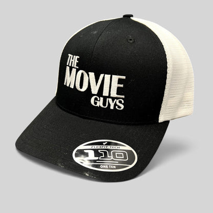 Raree Finds The Movie Guys black and white trucker hat with embroidered logo, mesh back, and Flexfit 110 sticker.