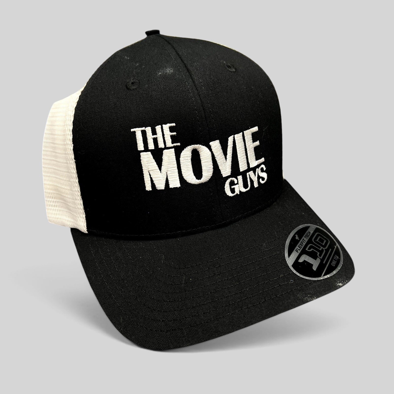 Raree Finds black and white The Movie Guys trucker hat with embroidered logo and breathable mesh back panels.