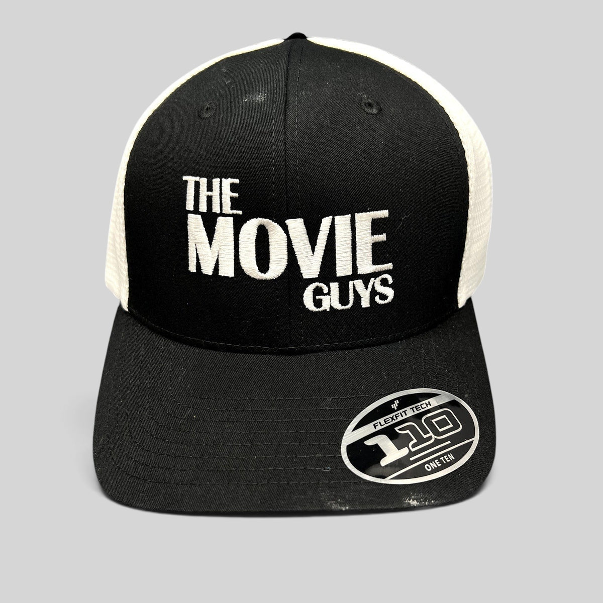 Raree Finds The Movie Guys black and white trucker hat with embroidered logo and Flexfit 110 snapback closure