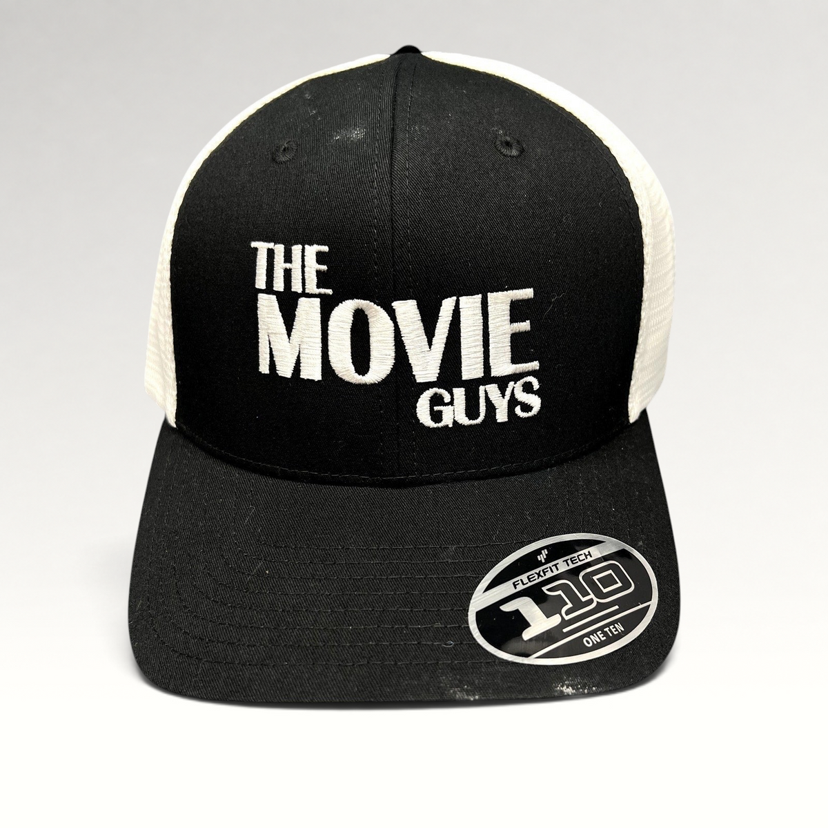 Raree Finds The Movie Guys black and white trucker hat with embroidered logo and Flexfit 110 snapback closure