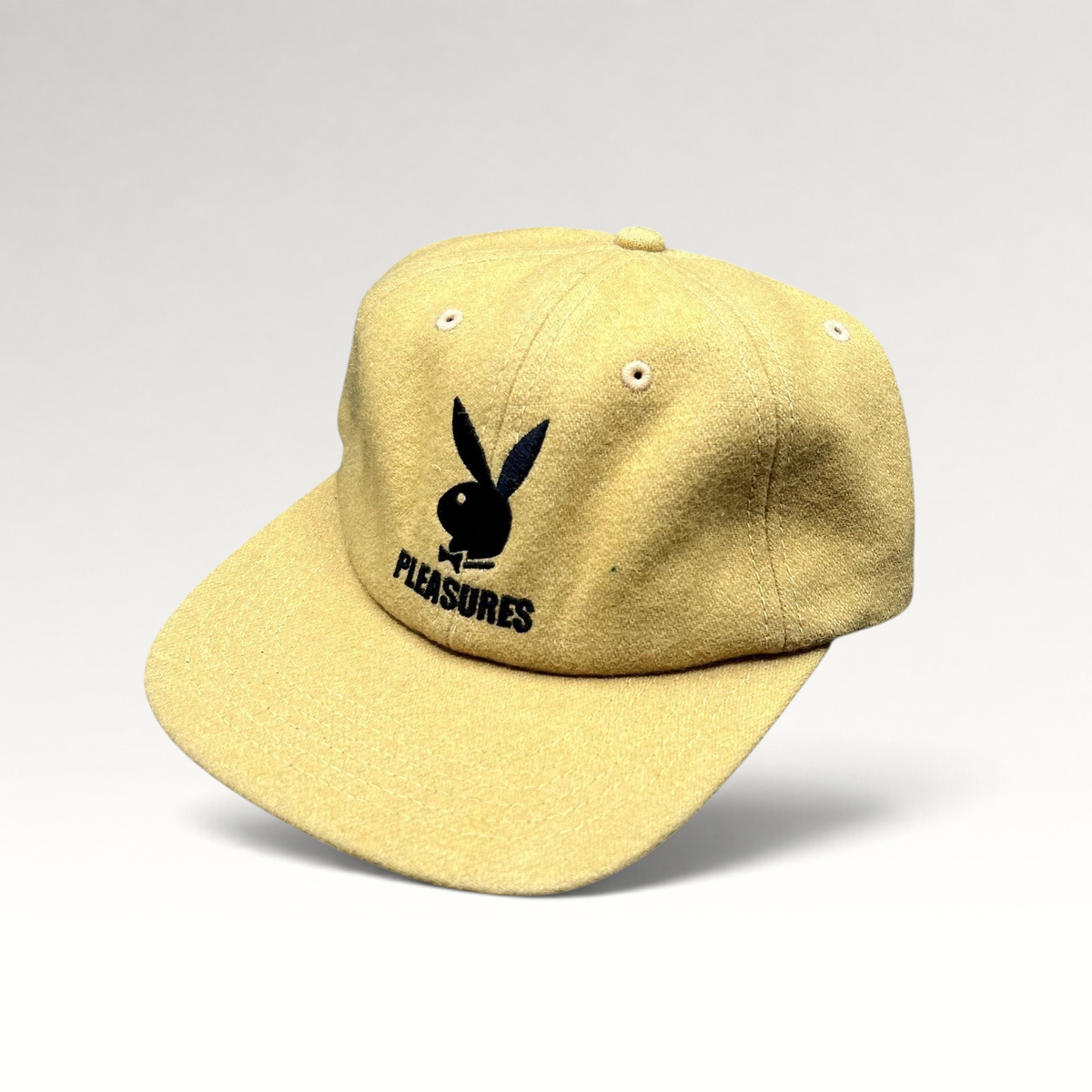 Raree Finds mustard Melton wool strapback hat with black embroidered Playboy Bunny and PLEASURES logo on front