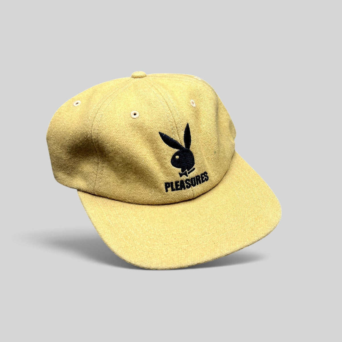 Raree Finds mustard Melton wool strapback hat featuring an embroidered black Playboy Bunny and PLEASURES logo.