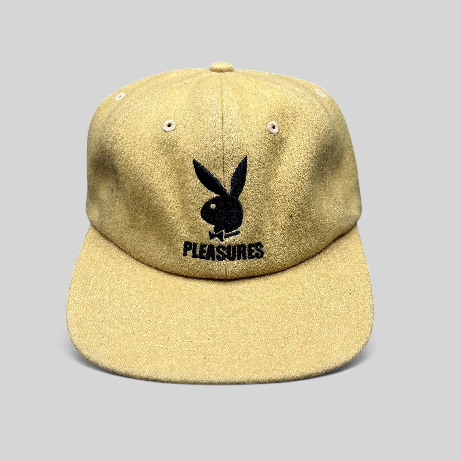 Raree Finds mustard Melton wool strapback hat featuring an embroidered black Playboy Bunny and PLEASURES logo.
