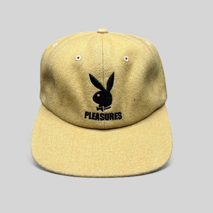 Raree Finds mustard Melton wool strapback hat featuring an embroidered black Playboy Bunny and PLEASURES logo.