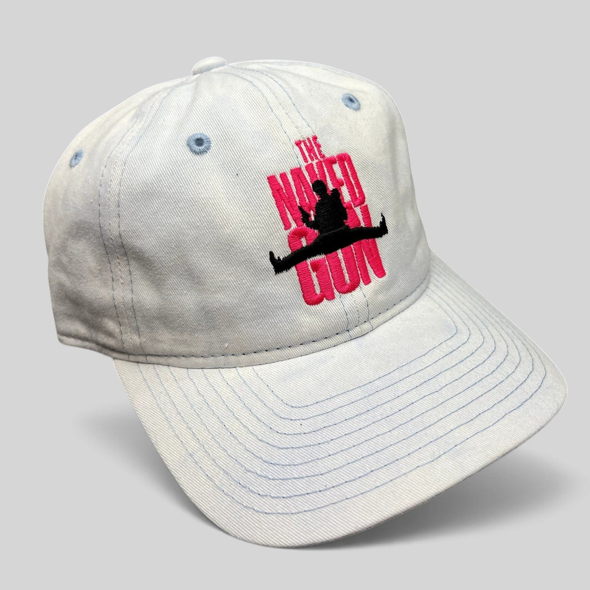Raree Finds white cotton strapback hat with pink The Naked Gun 2025 movie embroidery and light blue stitching.