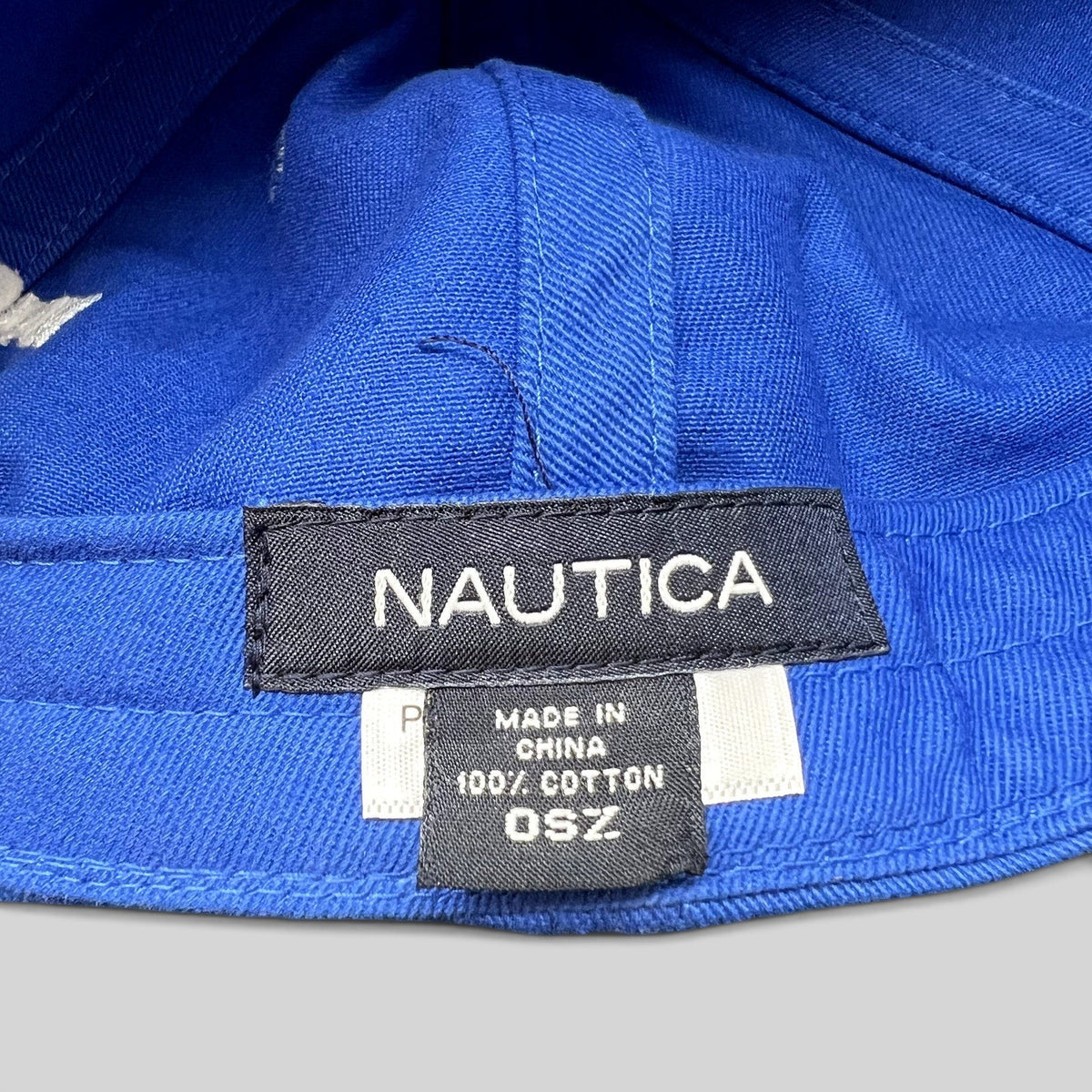 Raree Finds Nautica blue cotton hat interior label showing brand, material, and size details