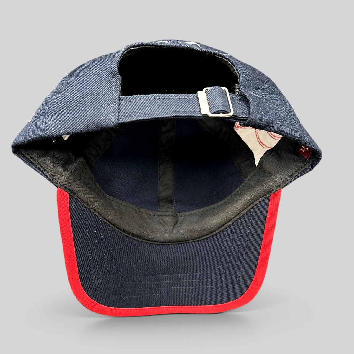 Raree Finds navy blue cotton strapback hat with red brim piping and adjustable metal buckle closure