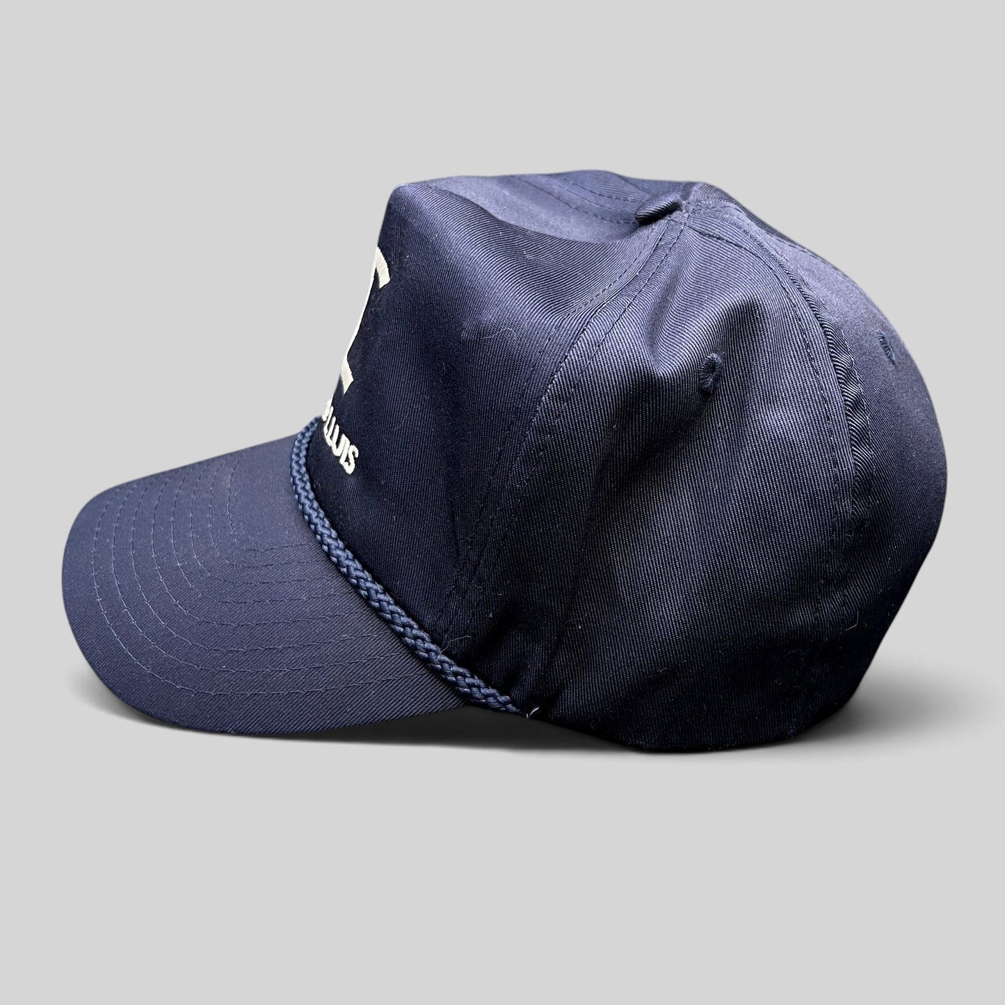 Raree Finds navy blue Cadiz & Lluis promotional snapback hat with white embroidered logo and braided rope bill detail.