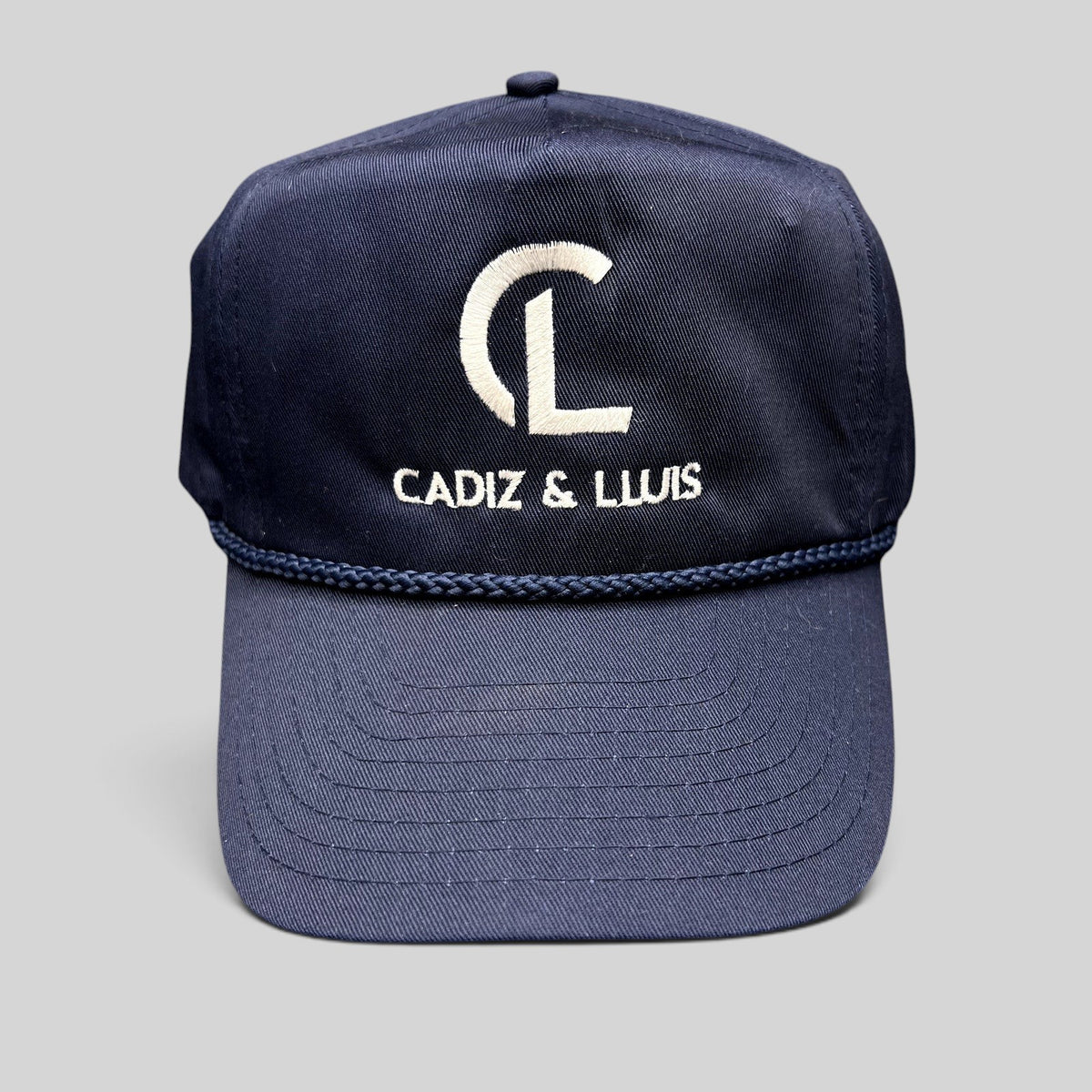 Raree Finds navy blue Cadiz & Lluis promotional snapback hat with white embroidered logo and braided rope bill detail