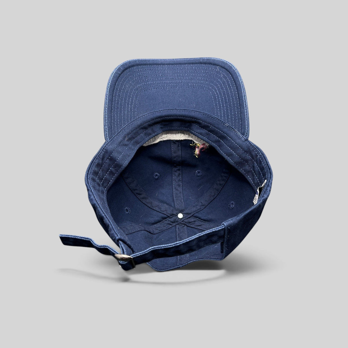 Raree Finds navy cotton dad hat showing the interior 6-panel construction, curved brim, and adjustable metal strap.