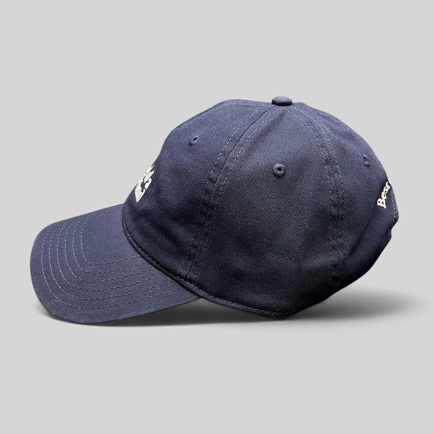 Raree Finds navy blue cotton twill dad hat with white embroidered text and curved brim, side profile view.