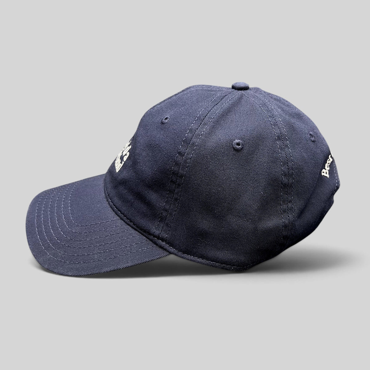 Raree Finds navy blue cotton twill dad hat with white embroidered text and curved brim, side profile view.