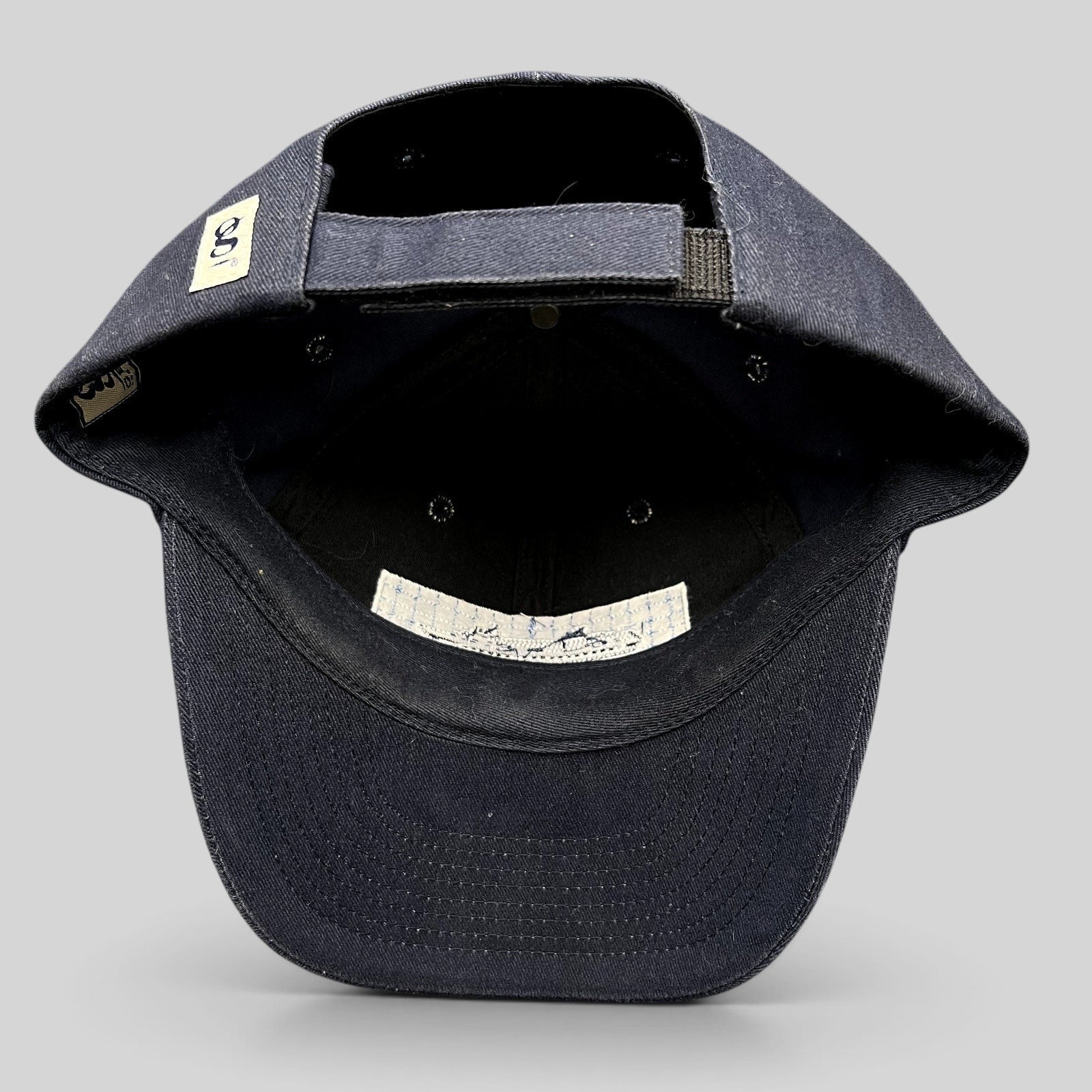 Raree Finds vintage navy blue cotton strapback hat showing the interior construction, adjustable strap, and branding.