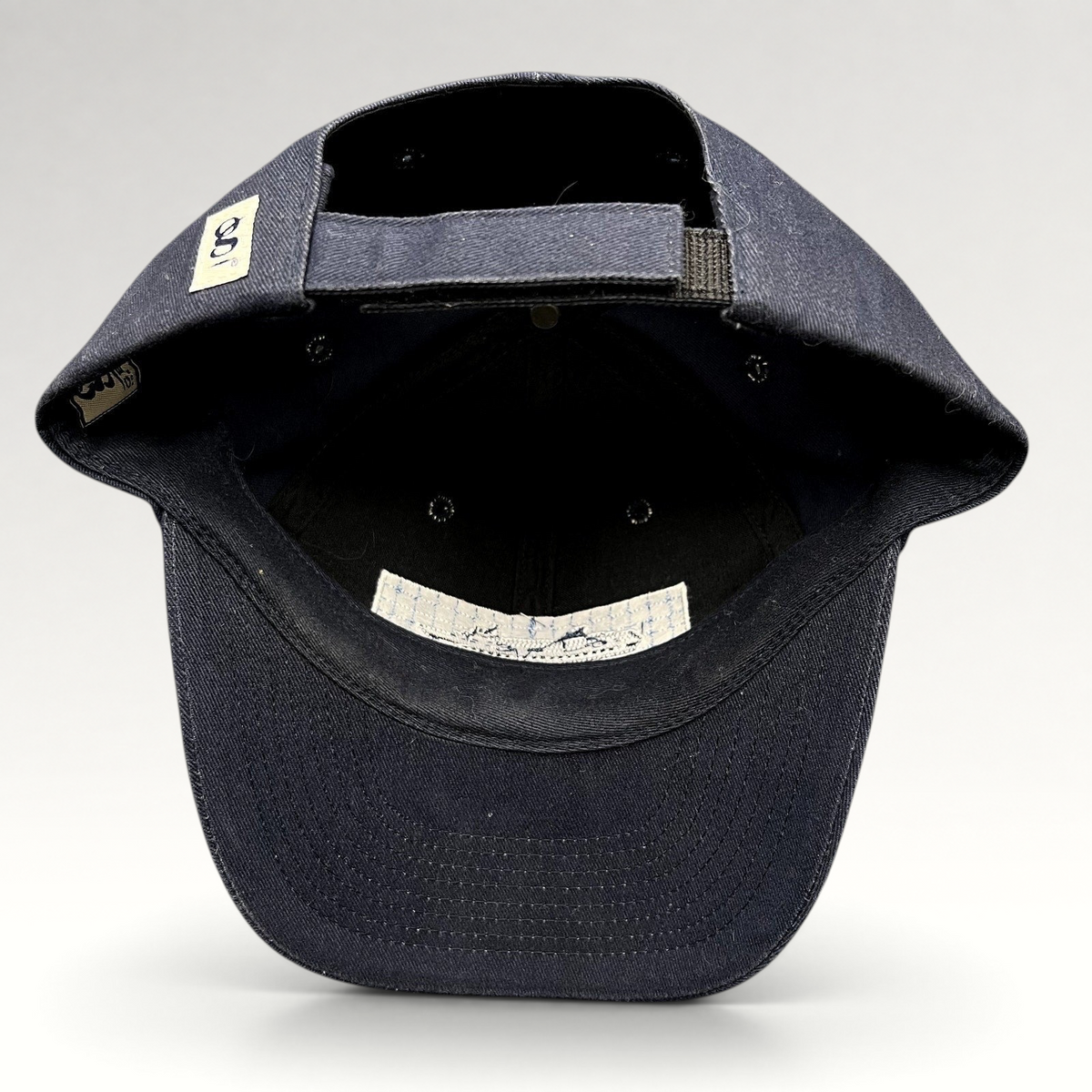 Raree Finds vintage navy blue cotton strapback hat showing the interior construction, adjustable strap, and branding.
