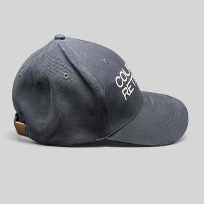Raree Finds navy cotton strapback hat with white Couples Retreat embroidery and brass clasp, side profile view.