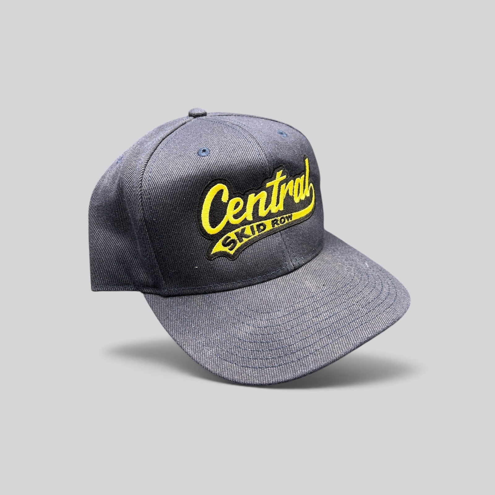 Raree Finds vintage 1990s navy blue denim snapback hat with yellow Central Skid Row embroidered script logo