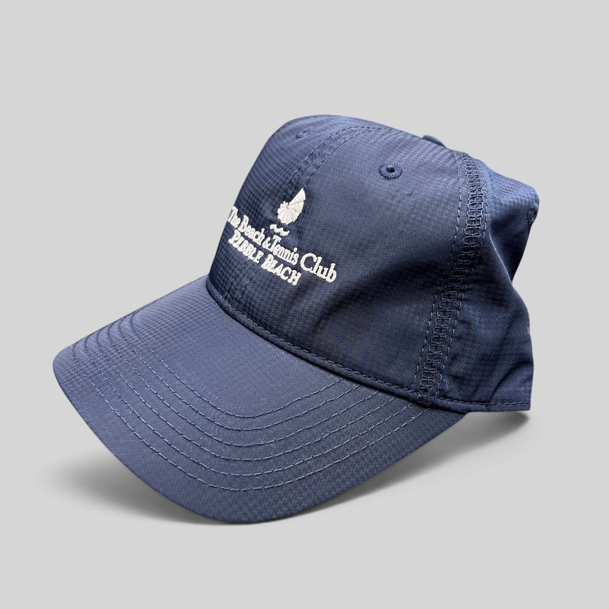 Raree Finds navy performance fabric cap with white embroidered Pebble Beach Beach & Tennis Club logo and curved brim