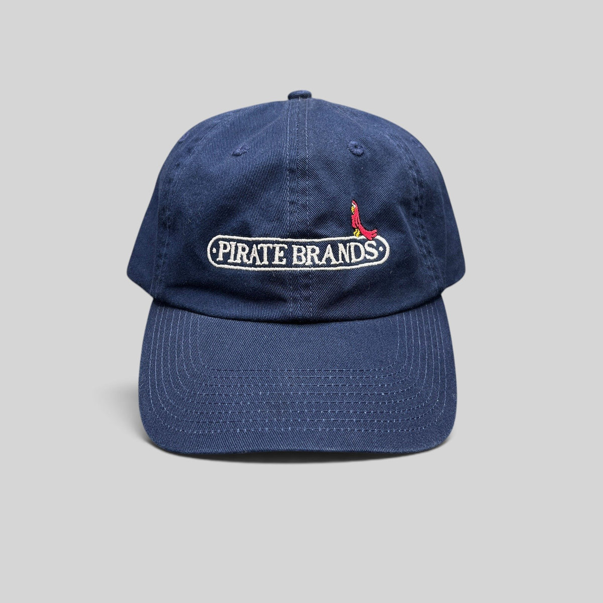 Raree Finds navy cotton dad hat with embroidered Pirate Brands logo and red parrot detail on a curved brim cap
