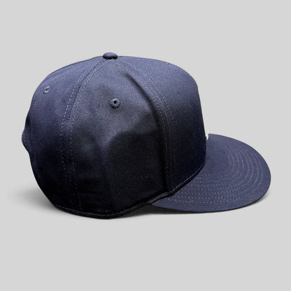 Raree Finds navy blue Quixote Studios snapback hat with a structured crown and flat brim, side profile view.