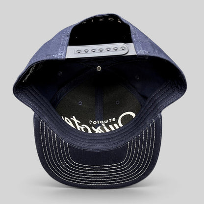 Raree Finds navy blue Quixote Studios snapback hat with white embroidered logo and adjustable plastic back closure