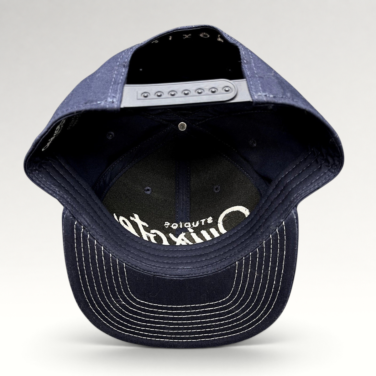 Raree Finds navy blue Quixote Studios snapback hat with white embroidered logo and adjustable plastic back closure