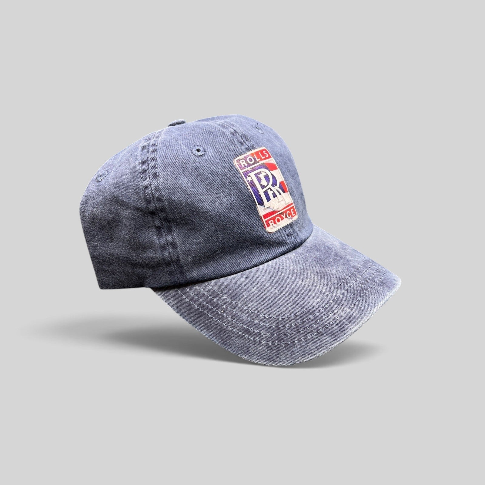 Raree Finds navy washed cotton dad hat with a patriotic Rolls-Royce crest patch and adjustable strap closure.