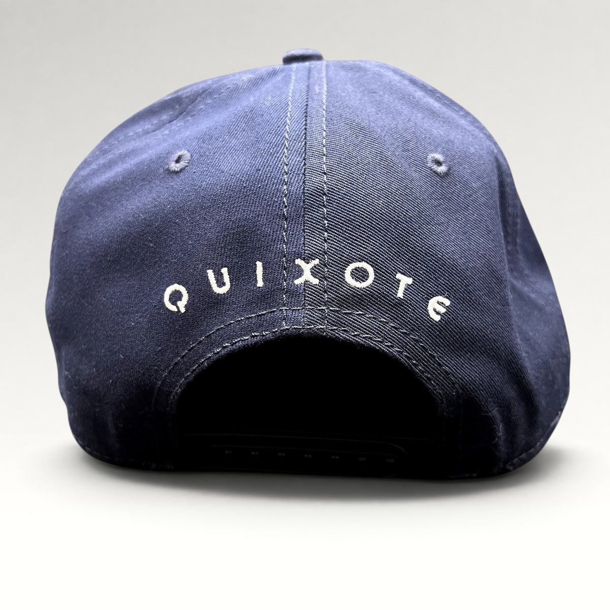 Raree Finds navy blue snapback hat featuring white Quixote embroidery on the back of the structured crown